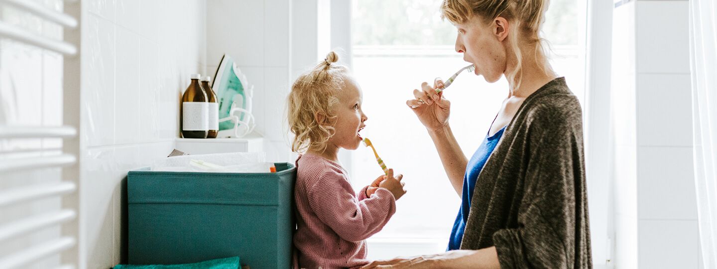 Mutter und Kind putzen zusammen Zähne