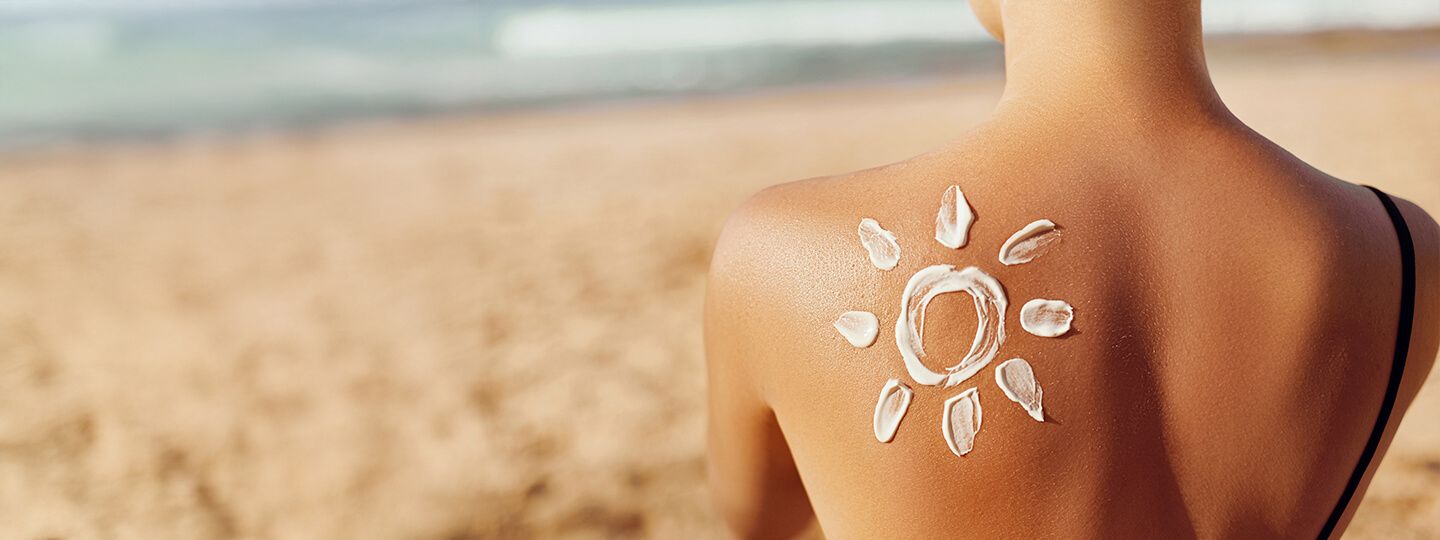 Person am Strand mit Sonnencreme auf dem Rücken